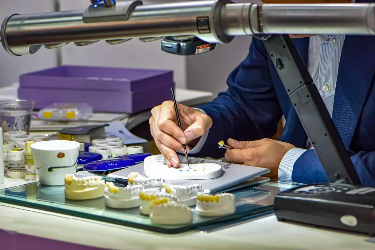 Tehnician dentar lucrează cu atenție la fațete ceramice, la masa unui laborator