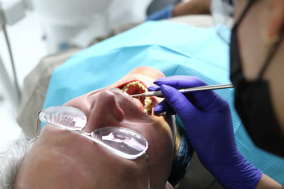 Pacient în fotoliul dentar, cu ochelari de protecție, în timpul unei intervenții orale