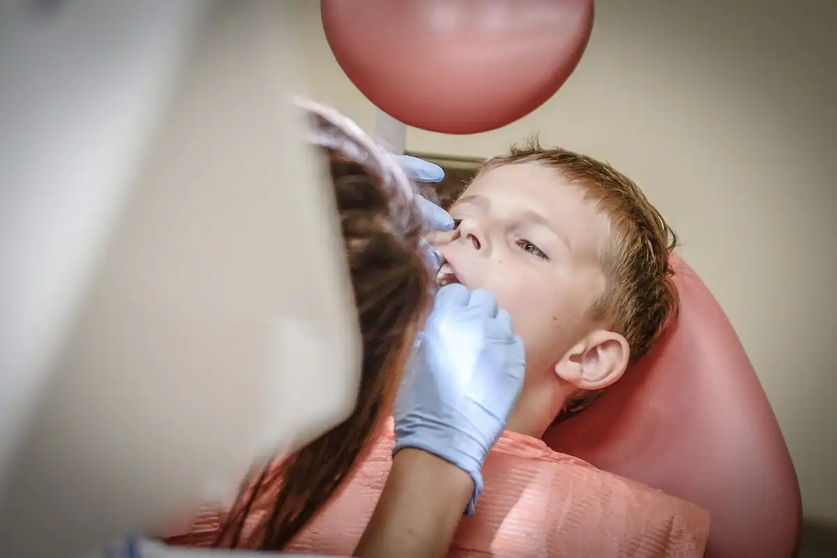 Copil examinat de medic în fotoliul dentar la un prim control