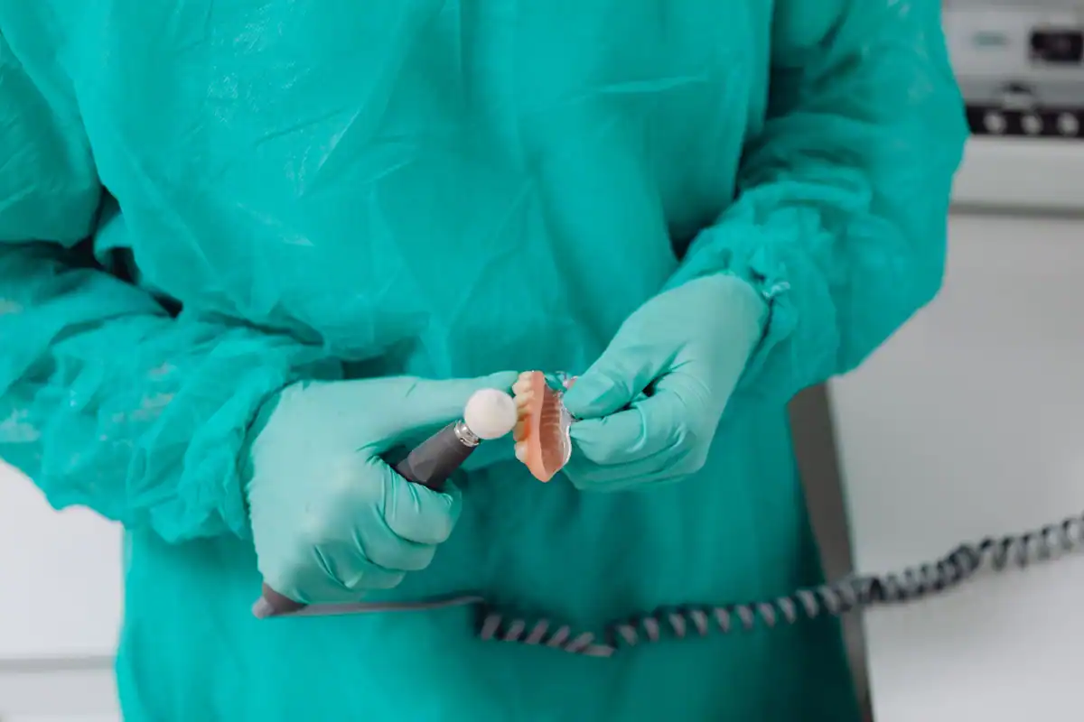 Tehnician dentar cu mănuși lustruiește cu grijă o proteză dentară