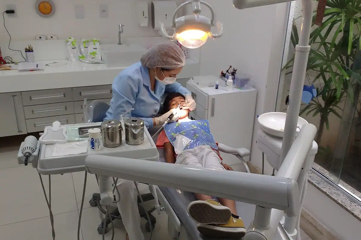 Medic stomatolog tratează un pacient într-un cabinet cu unit dentar și lampă